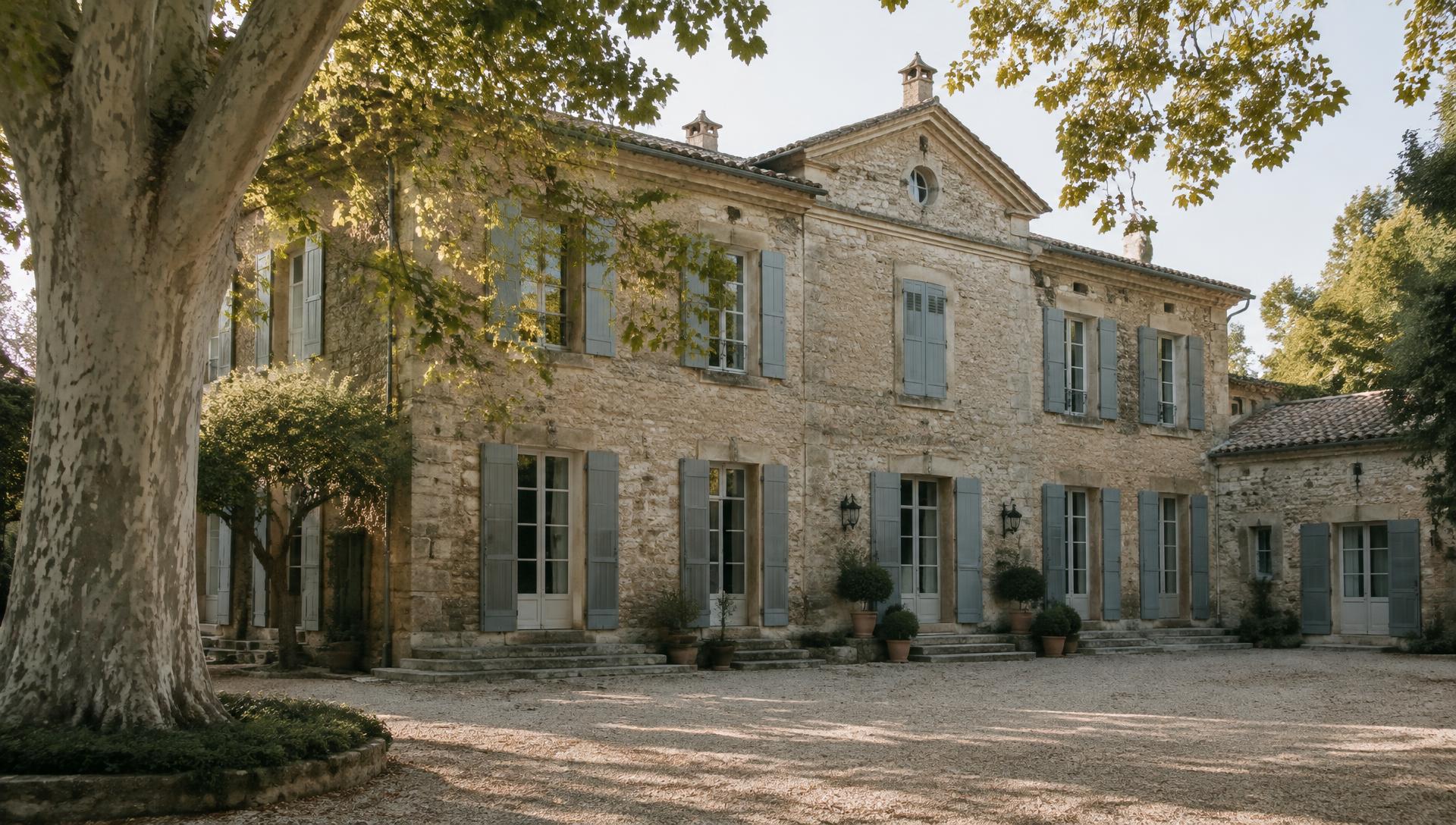 Bastide provençale en pierre aux volets gris-bleu, sous les platanes